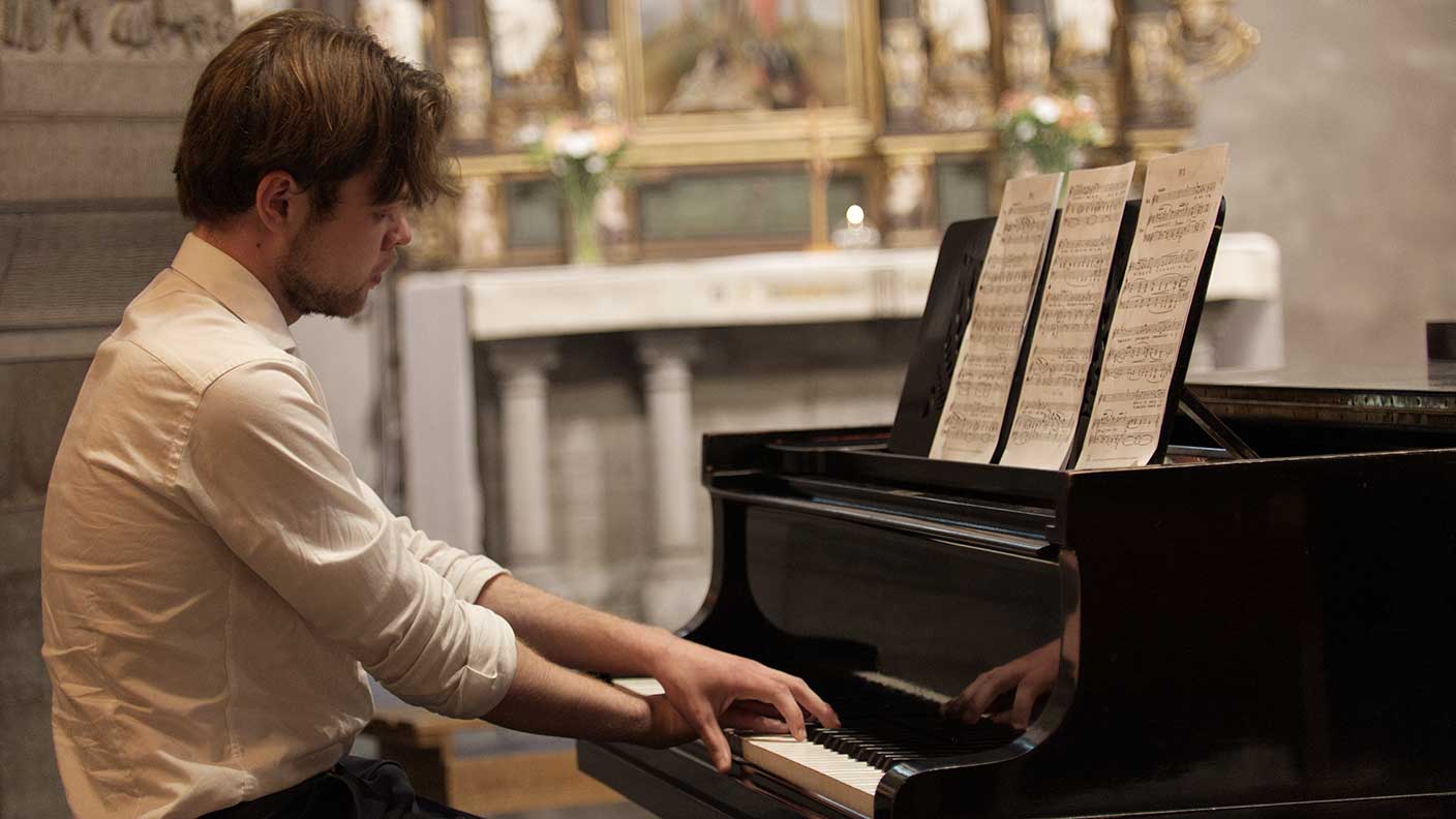Man i vit skjorta spelar piano i kyrka.