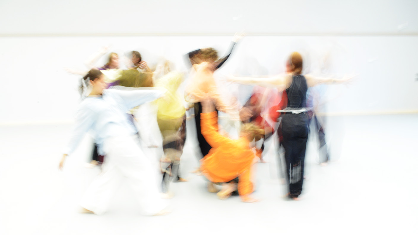 Blurrad bild på tiotal personer som dansar i ljust rum.