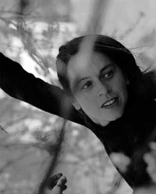 Kvinna med mörkt hår och mörkklädd i snår.