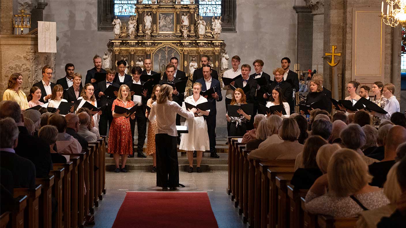 30 personer sjunger körsång i kyrka framför sittande församling.