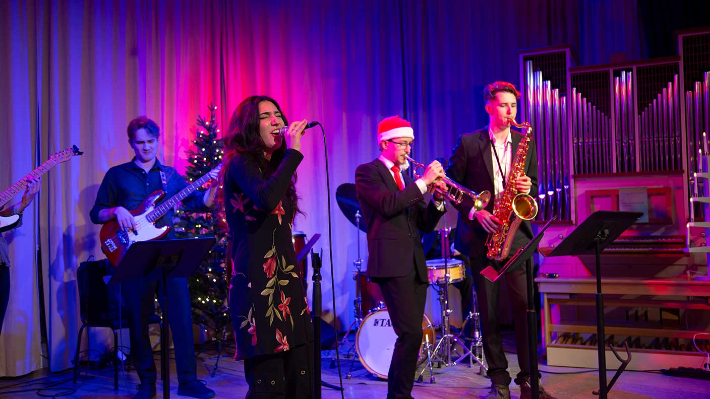 Unga musikanter på julpyntad scen i lila scenljus.