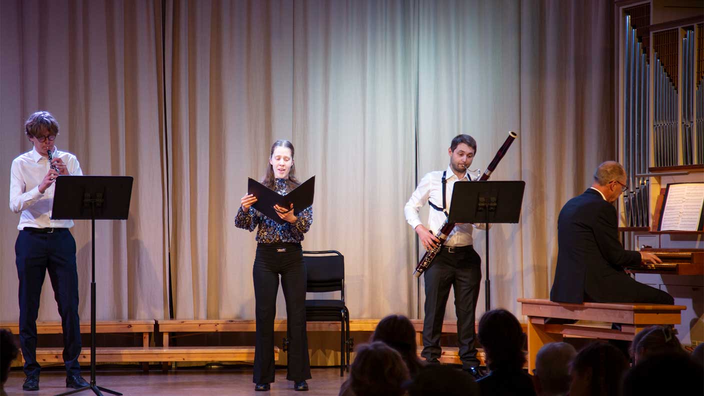 Fyra personer på scen framför musik med sång, oboe, fagott och piano.