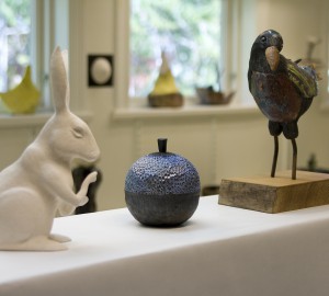Vit keramikkanin, blå keramikvas och fågel i keramik