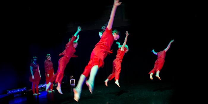 Fyra dansare "hänger i luften" med utsträcka ben och armar.