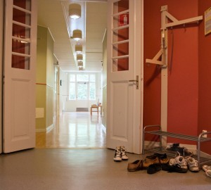 En bild av en korridor i huset Internatet. I förgrunden skoställ.