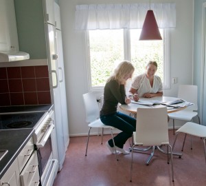 Två deltagare sitter och arbetar vid matbordet i köket i Villan.
