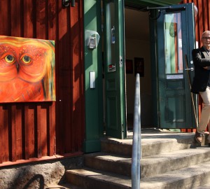 Konsthusets dörrar står öppna, en lärare stå utanför. På husets fasad hänger en röd tavla med en målad fågel.