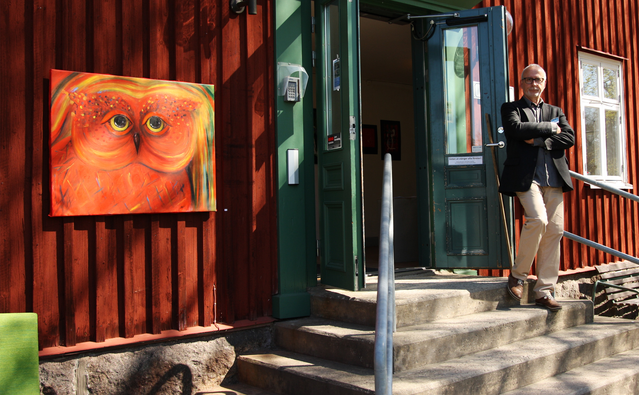 Konsthusets dörrar står öppna, en lärare stå utanför. På husets fasad hänger en röd tavla med en målad fågel.