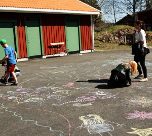 Besökare ritar på asfalten med färgade kritor.