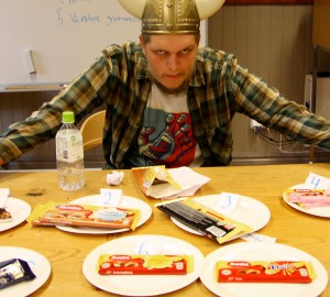 Bord med chokladkakor på papperstallrikar. I bakgrunden en deltagare i vikingahjälm.