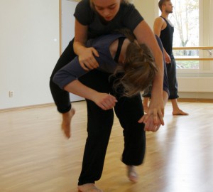 En dansare ligger på mage över en annans rygg.