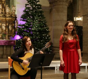 Duo med klassisk gitarr och sång. I bakgrunden en julgran och kyrkovalv.