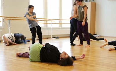 Flera dansare på golvet. Tre stående. En av de liggande, på sidan, är Hagit Yakira som leder workshopen.