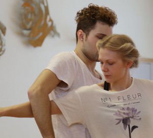 En dansare sträcker sin arm igenom bågen som en annan dansares arm bildar.