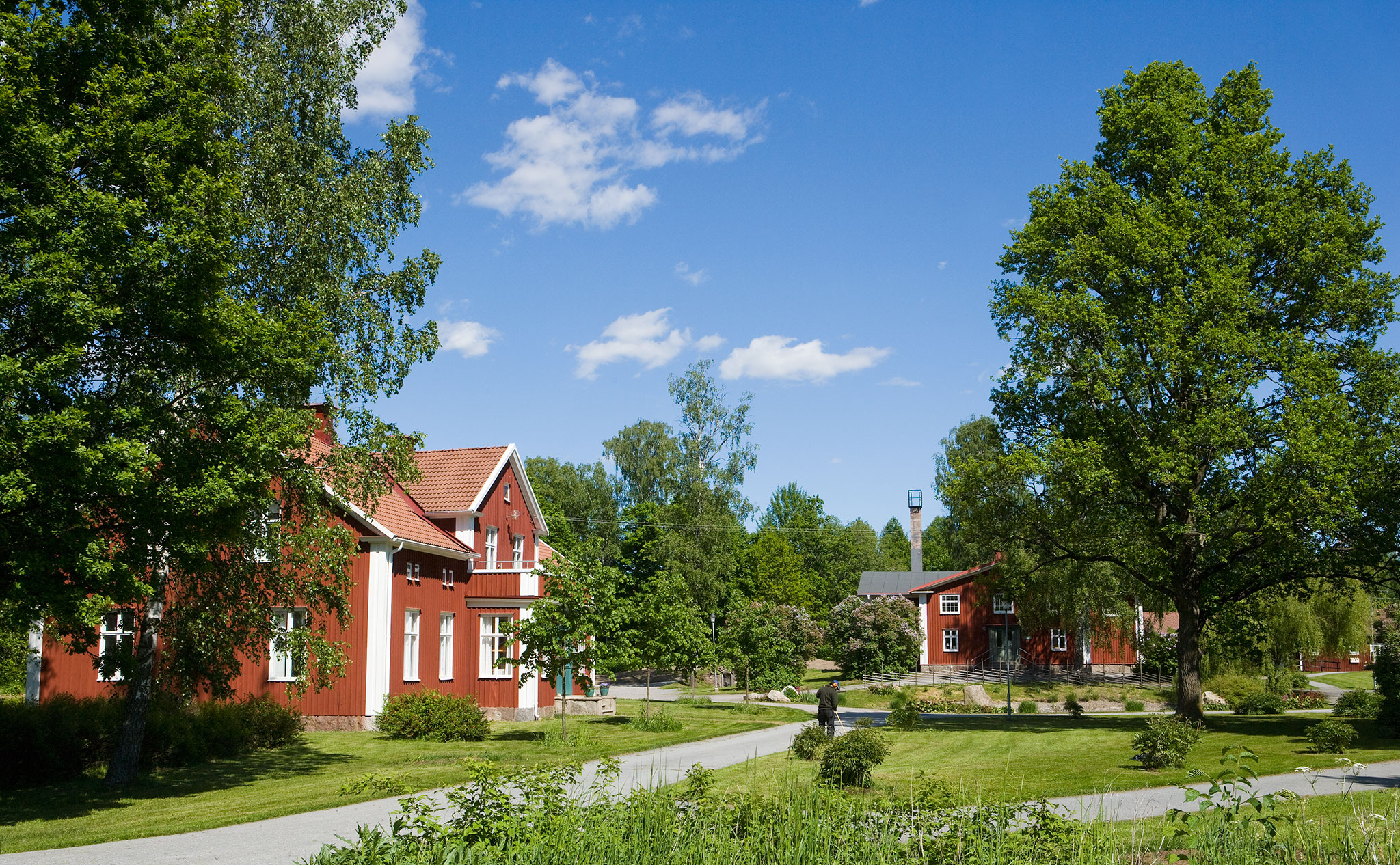 Miljöbild Kävesta - Hantverkshuset omgivet av sommargröna träd och gräsmattor