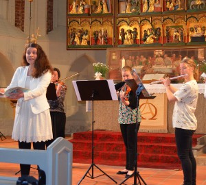 Deltagare sjunger och spelar stråkinstrument i en kyrka.