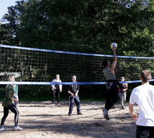 Flera personer spelar volleyboll i sanden.
