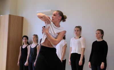 Dansare gör en rullande rörelse med händerna, nära kroppen.