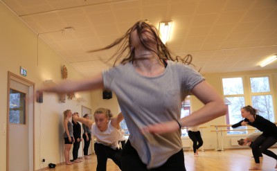Dansare i förgrunden med huvudet bakåtkastat och håret för ansiktet.