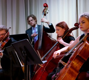 En del av en stråkorkester, fyra deltagare på fiol, basfiol och cello.