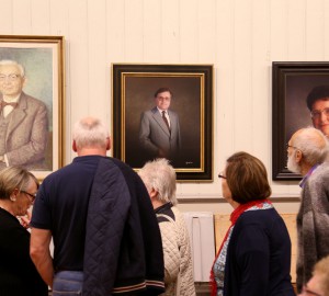Flera personer står framför porträtt av gamla rektorer på Kävesta.