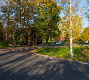 En väg som leder av in bland träd och röda hus.