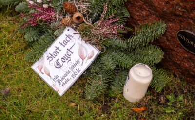 På en krans med barr, kottar och andra växter ligger ett laminerat kort där det står "Stort tack Coyet. Från Kävesta folkhögskola, 150 år".