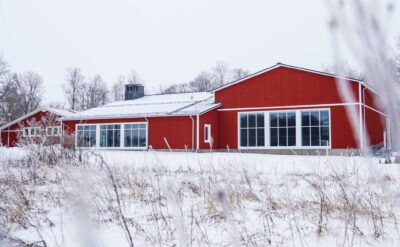 Rött hus med två stora fönsterytor, i ett vinterlandskap.